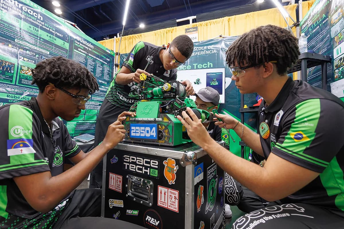 FIRST Tech Challenge students making adjustments to their robot in the pits